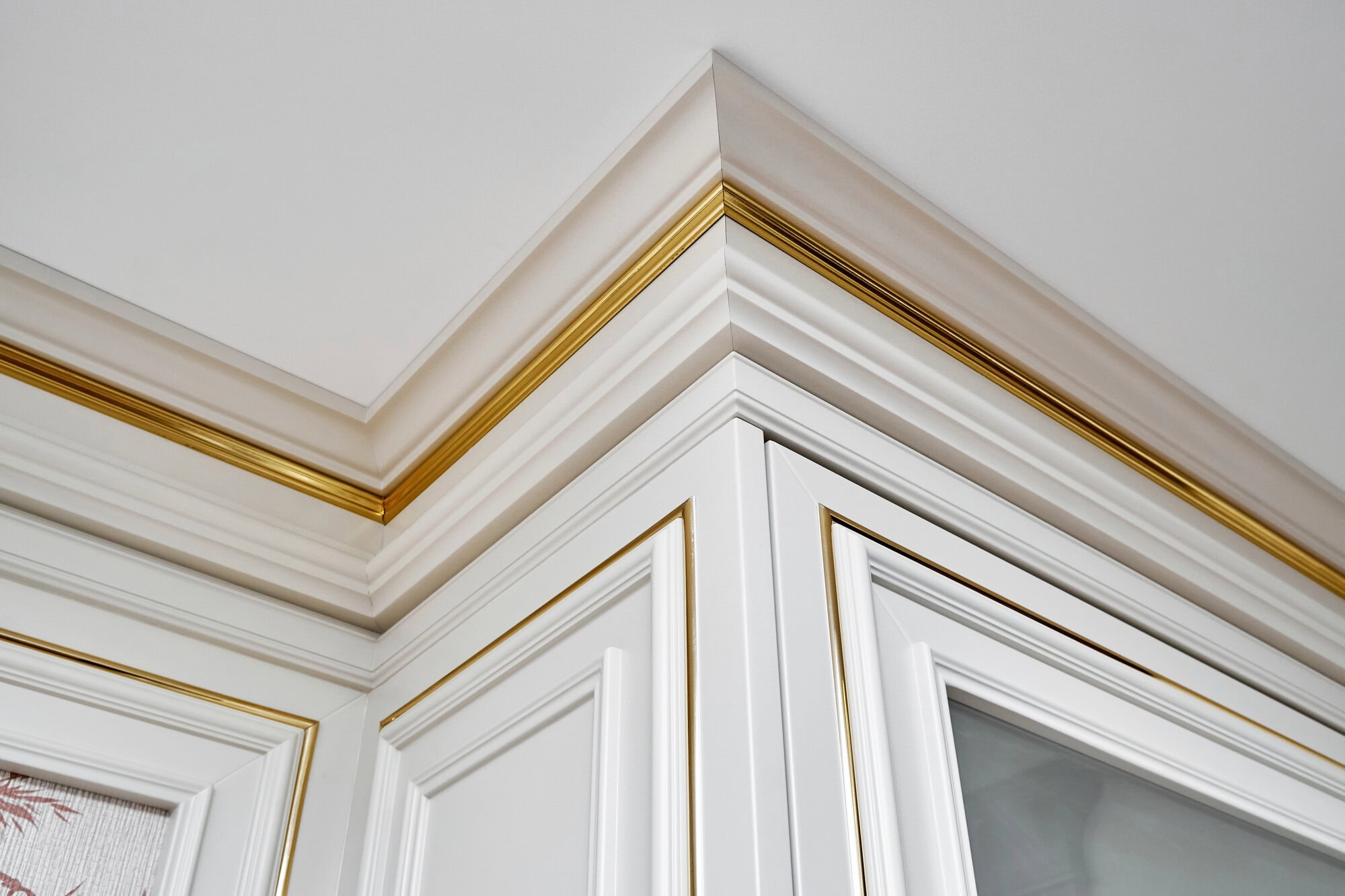 Vintage display case with crown molding and glass door in classic style and vintage wall panel with golden molding in light spacious room closeup